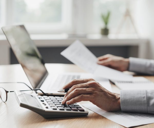 Businessman accountant, financial advisor or banker making calculations Man using calculator with computer laptop, budget and loan paper in office. Business accounting, bills, home budget, tax, savings, finances, economy, audit, debt concept