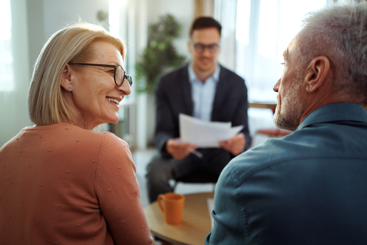 Elderly couple smiling during financial consultation with advisor.