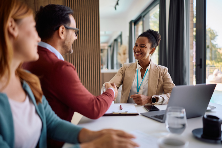 Business meeting handshake between diverse professionals at modern office table.