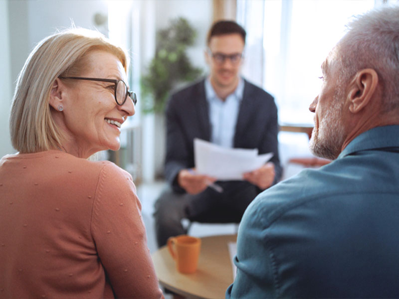 Older couple discussing paperwork with a consultant in an office setting.