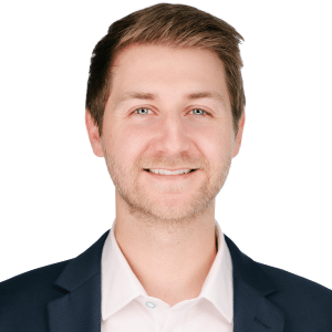 A smiling man in a suit and white shirt against a white background.