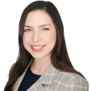 A woman in a gray plaid blazer smiling against a white background.