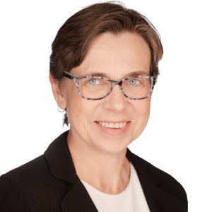 A woman with glasses and short hair wearing a black blazer smiles in a professional headshot.